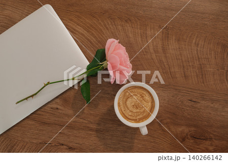 flat lay of coffee, pink rose, and closed laptop: cozy atmosphere for autumn remote work flat lay of coffee, pink rose, and closed laptop: cozy atmosphere for autumn remote work 140266142