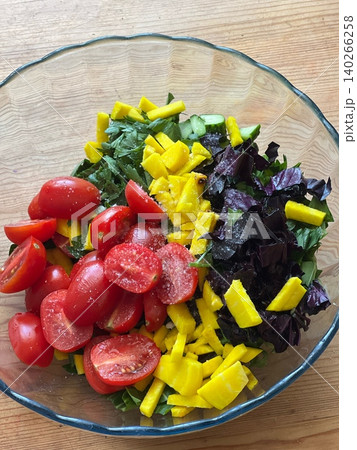 Fresh vegetable salad with tomatoes, mango, and herbs in glass bowl 140266258