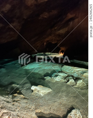 Cave interior with water pool and rocky formations illuminated by light Cave interior with water pool and rocky formations illuminated by light 140266265