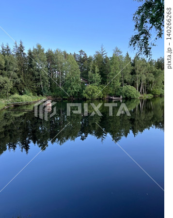 Tranquil lake surrounded by lush trees and clear blue sky reflections Tranquil lake surrounded by lush trees and clear blue sky reflections 140266268