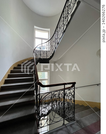 Elegant staircase with ornate railing and natural light from window Elegant staircase with ornate railing and natural light from window 140266276