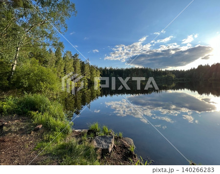 Scenic lake view with reflections of trees and clouds in the water 140266283