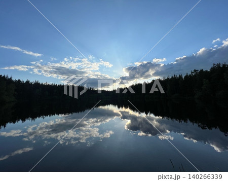 Serene lake landscape reflecting clouds and trees under blue sky 140266339