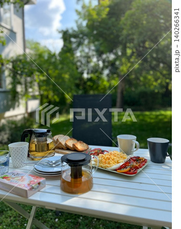 Breakfast table setting with tea, bread, and vegetables in garden 140266341
