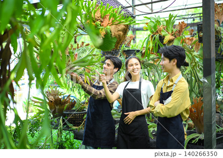 Team of gardeners discussing plant care in greenhouse, showing teamwork and knowledge sharing 140266350