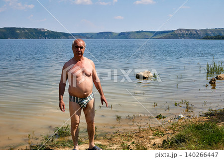 Cheerful elderly pensioner loves to swim in the summer river Cheerful elderly pensioner loves to swim in the summer river 140266447