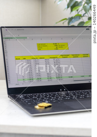 Laptop Showing Monthly EMI Calculations Next to Stacked Coins Laptop Showing Monthly EMI Calculations Next to Stacked Coins 140266449