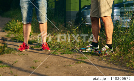 Two people.Men meet outdoor.Leisurely conversation.Shorts and sneakers. Two people.Men meet outdoor.Leisurely conversation.Shorts and sneakers. 140266673
