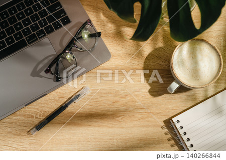 Home office workspace with open notebook, coffee and eyeglasses on wooden desk, top view with copy space Home office workspace with open notebook, coffee and eyeglasses on wooden desk, top view with copy space 140266844