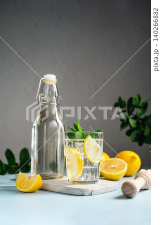 Lemon infused water with mint in glass beside bottle, healthy hydration and wellness concept 140266882