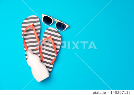 Flip-flops with sunscreen and sunglasses on blue background 140267135