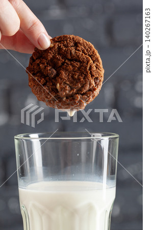 Female hand dunking cookie in milk close up Female hand dunking cookie in milk close up 140267163