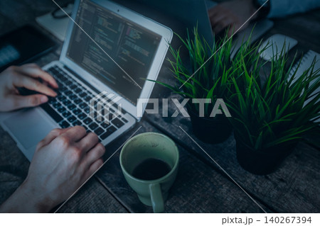 Coding session at a desk with coffee and plants in the workspace 140267394