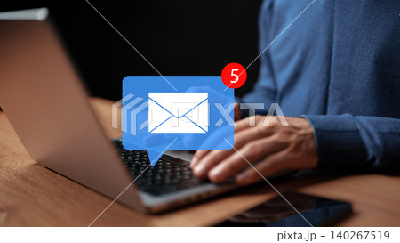 Person checking emails on a laptop while sitting at a wooden table at night Person checking emails on a laptop while sitting at a wooden table at night 140267519