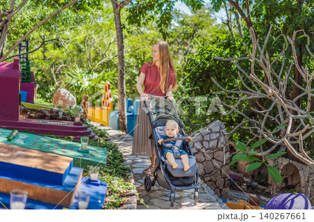 Woman pushing baby stroller through traditional Mexican cemetery during Day of the Dead, exploring colorful cultural heritage with her infant in Mexico 140267661