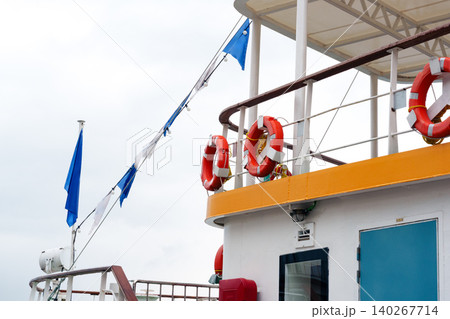 Boat deck with safety equipment and flags on a cloudy day in open water 140267714