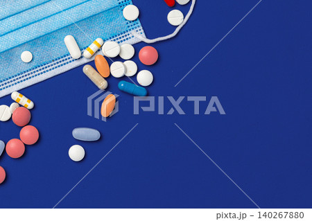 Different types of pills and a medical mask on a blue background Different types of pills and a medical mask on a blue background 140267880