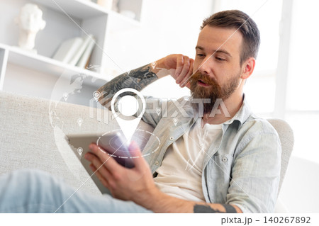 Man checking travel route for taxi on tablet at home during the day Man checking travel route for taxi on tablet at home during the day 140267892