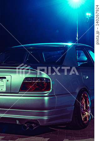 Car parked under blue lights at night on a city street with glowing rims Car parked under blue lights at night on a city street with glowing rims 140267924