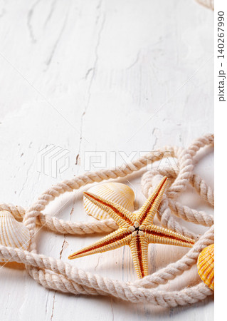 Starfish and seashells on white wood surface with rope arranged in a coastal scene 140267990