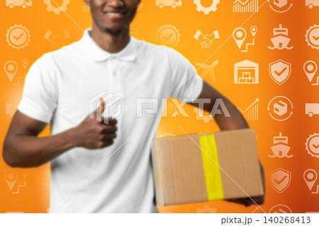 Smiling worker holding a box in front of logistics themed background during daytime Smiling worker holding a box in front of logistics themed background during daytime 140268413