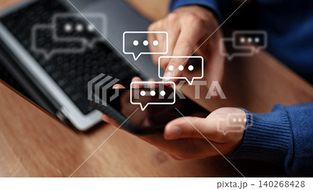 Sending messages on a smartphone while sitting at a desk with a computer nearby 140268428