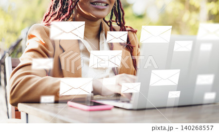 Woman writing emails on laptop with messages appearing in the air in the park 140268557