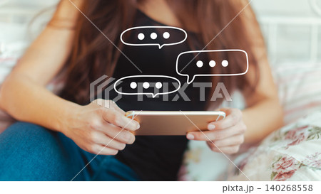Person using phone to read messages while sitting on a bed with a floral pattern Person using phone to read messages while sitting on a bed with a floral pattern 140268558
