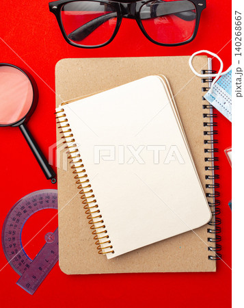 Office supplies on a red table with notebook, glasses, and tools for studying and writing Office supplies on a red table with notebook, glasses, and tools for studying and writing 140268667