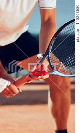 Player holds tennis racket preparing for a serve during a match on a court in the morning Player holds tennis racket preparing for a serve during a match on a court in the morning 140268680