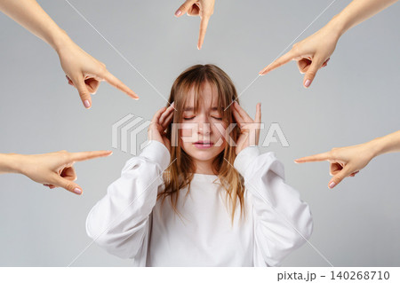 Girl holding her head with hands pointing at her in a simple studio setting Girl holding her head with hands pointing at her in a simple studio setting 140268710