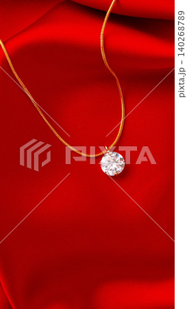 Elegant necklace with clear pendant on red fabric background Elegant necklace with clear pendant on red fabric background 140268789
