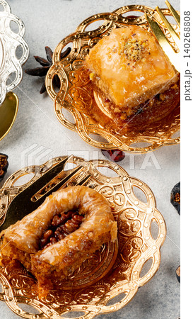 Baked sweets on golden plates with nuts and syrup arranged on a gray surface Baked sweets on golden plates with nuts and syrup arranged on a gray surface 140268808