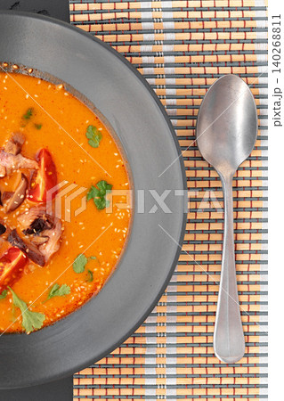Delicious soup served in a bowl with chicken and herbs on a table with a spoon nearby Delicious soup served in a bowl with chicken and herbs on a table with a spoon nearby 140268811