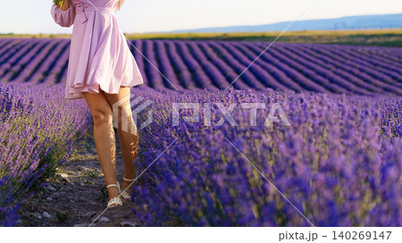 Woman walks through a lavender field in the daytime with rows of flowers Woman walks through a lavender field in the daytime with rows of flowers 140269147
