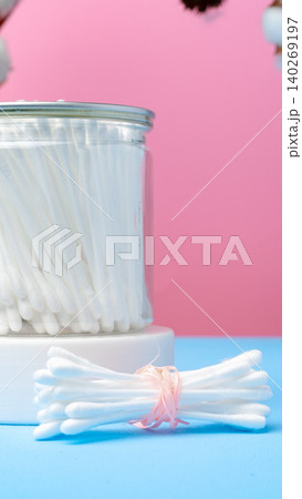 Personal care items are organized in a clear jar with a pink and blue background 140269197