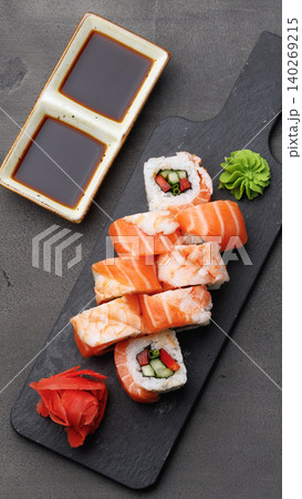 Sushi rolls served on a black plate with dipping sauce and garnish in a restaurant setting 140269215