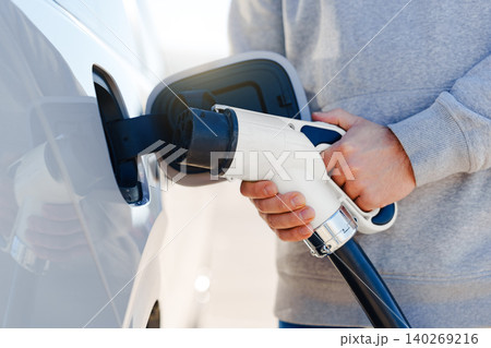 Charging an electric car at a charging station during daytime Charging an electric car at a charging station during daytime 140269216