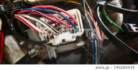 Automotive electrical connector with multiple colored wires visible, showcasing intricate wiring details and connections in a close-up view of a vehicle's electrical system Automotive electrical connector with multiple colored wires visible, showcasing intricate wiring details and connections in a close-up view of a vehicle's electrical system 140269438