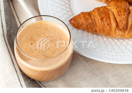 Tasty croissant with cup of coffee with milk on kitchen table Tasty croissant with cup of coffee with milk on kitchen table 140269636