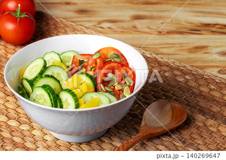 Ceramic bowl of tomato and cucumber salad on table 140269647