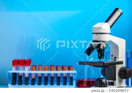 Close up photo of microscope with test tubes with blood samples Close up photo of microscope with test tubes with blood samples 140269657