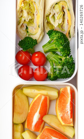 Healthy lunch box with wraps, vegetables, and fruit at midday meal time Healthy lunch box with wraps, vegetables, and fruit at midday meal time 140269726