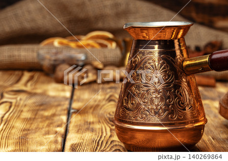 Shiny copper turk with brewed coffee on brown wooden table 140269864