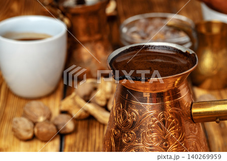 Shiny copper turk with brewed coffee on brown wooden table 140269959