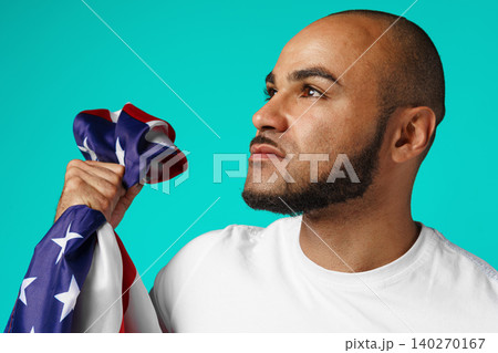 Portrait of young dark-skinned man proudly holding USA flag 140270167