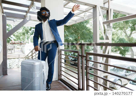 Black man in formal suit with packed suitcase entering hotel door Black man in formal suit with packed suitcase entering hotel door 140270177