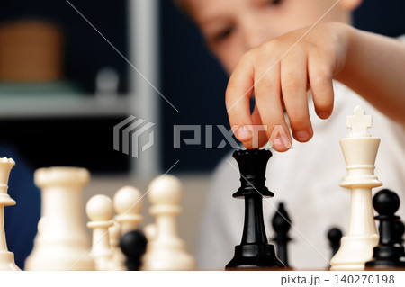 Close up photo of a little boy playing chess 140270198