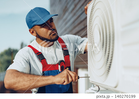 Young black man repairman checking an outside air conditioner unit Young black man repairman checking an outside air conditioner unit 140270199