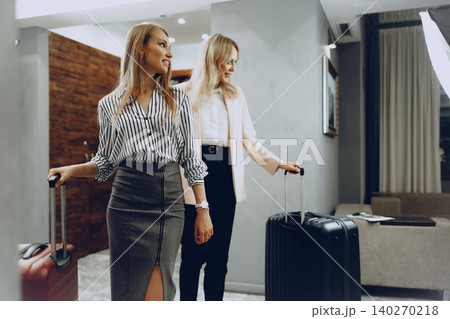 Two young women in formal clothes entering hotel lobby 140270218